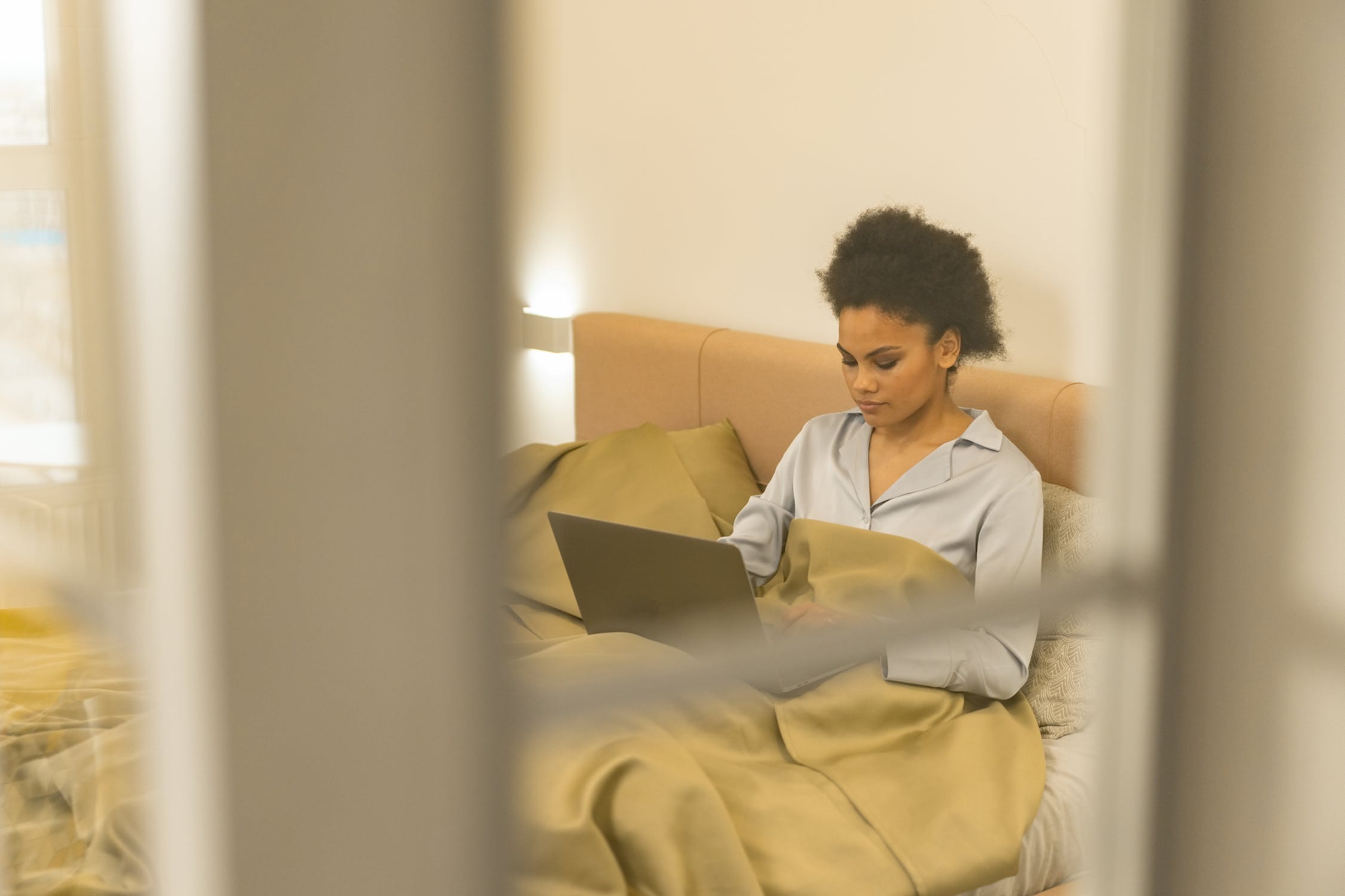 Black woman on bed working on laptop