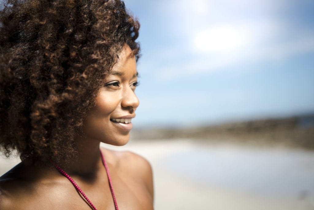Close-up of thoughtful woman smiling at beach